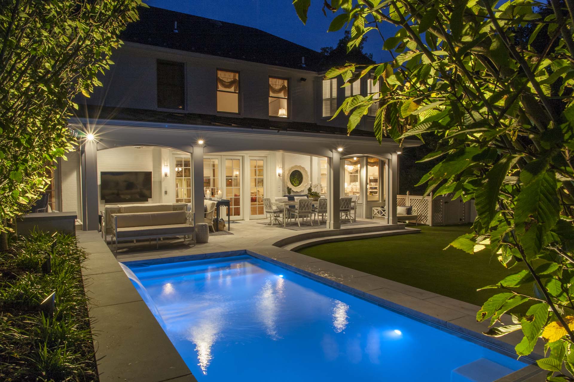 Pool in backyard with waterfall and colorful lighting